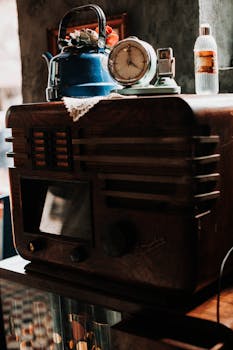 Retro wooden radio adorned with a vintage tea kettle, clock, and bottle. Warm vintage ambiance.