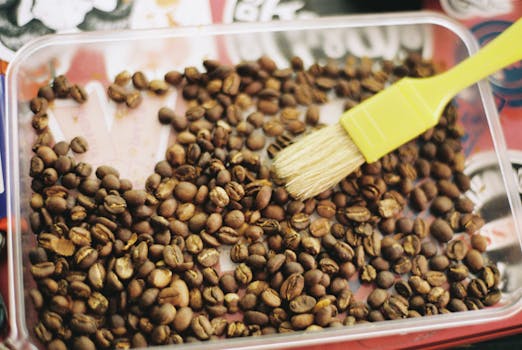 A tray filled with roasted coffee beans and a brush, emphasizing coffee aroma and preparation.
