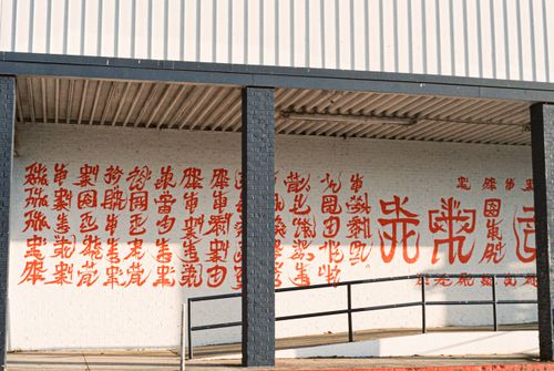 Free Vivid Chinese calligraphy in red on an outdoor wall creates an artistic display. Stock Photo
