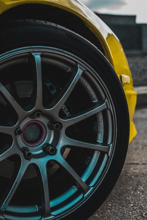 Free Detailed view of a stylish alloy wheel and tire on a yellow sports car, showcasing modern automotive design. Stock Photo