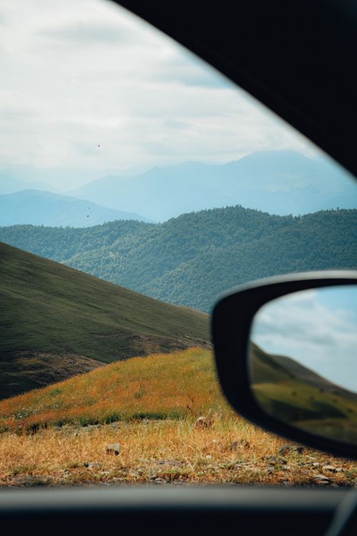 Free Breathtaking view of rolling hills and mountains from a car window, showcasing nature's beauty. Stock Photo