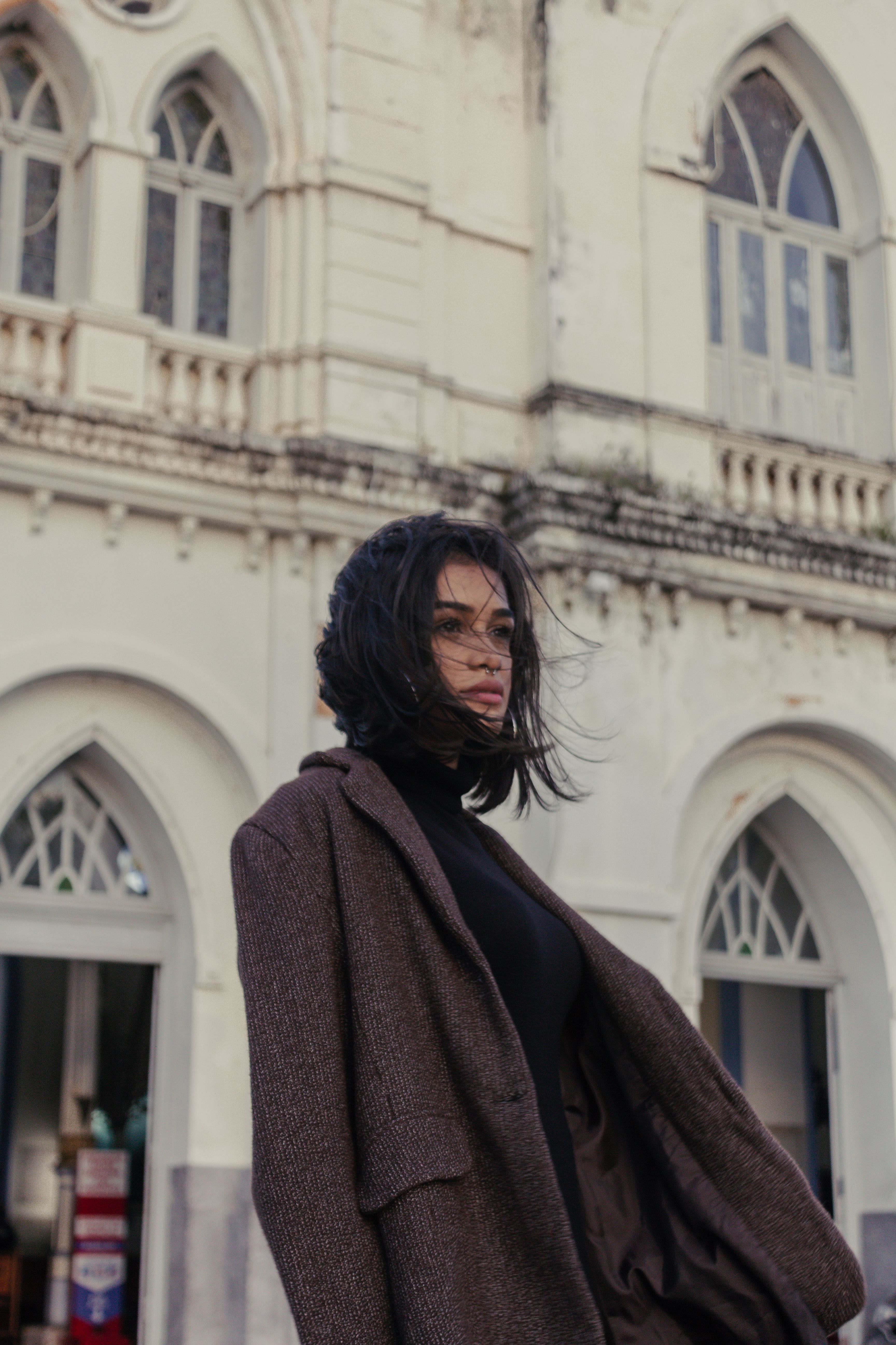 Woman in Brown Coat Standing Near the Concrete Building · Free Stock Photo