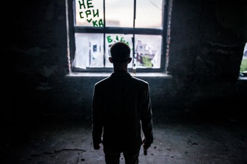 Free Silhouetted man stands alone by a window in a dark room. Stock Photo