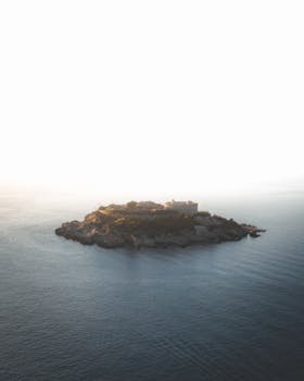 Aerial photo of Sveti Stefan Island in Montenegro during a serene sunrise over the Adriatic Sea.