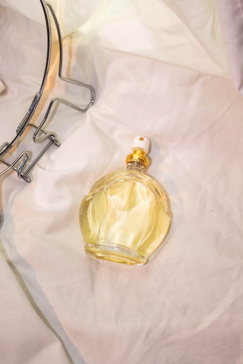 Clear Glass Perfume Bottle on the Bed