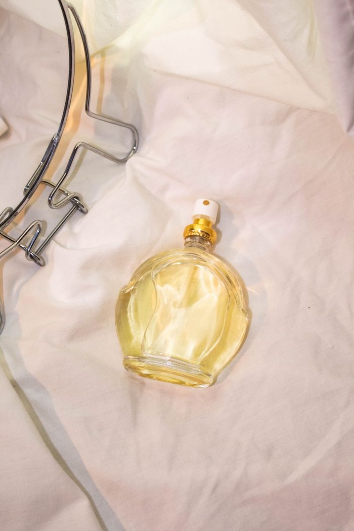Fragrance bottle resting on soft folded fabric — photo by Eve on Pexels