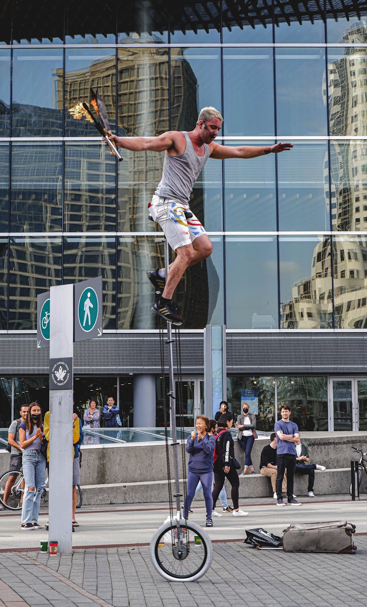 Man Balancing High On Unicycle 
