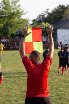 A soccer referee holds up a flag on the field during a game, signaling to players.