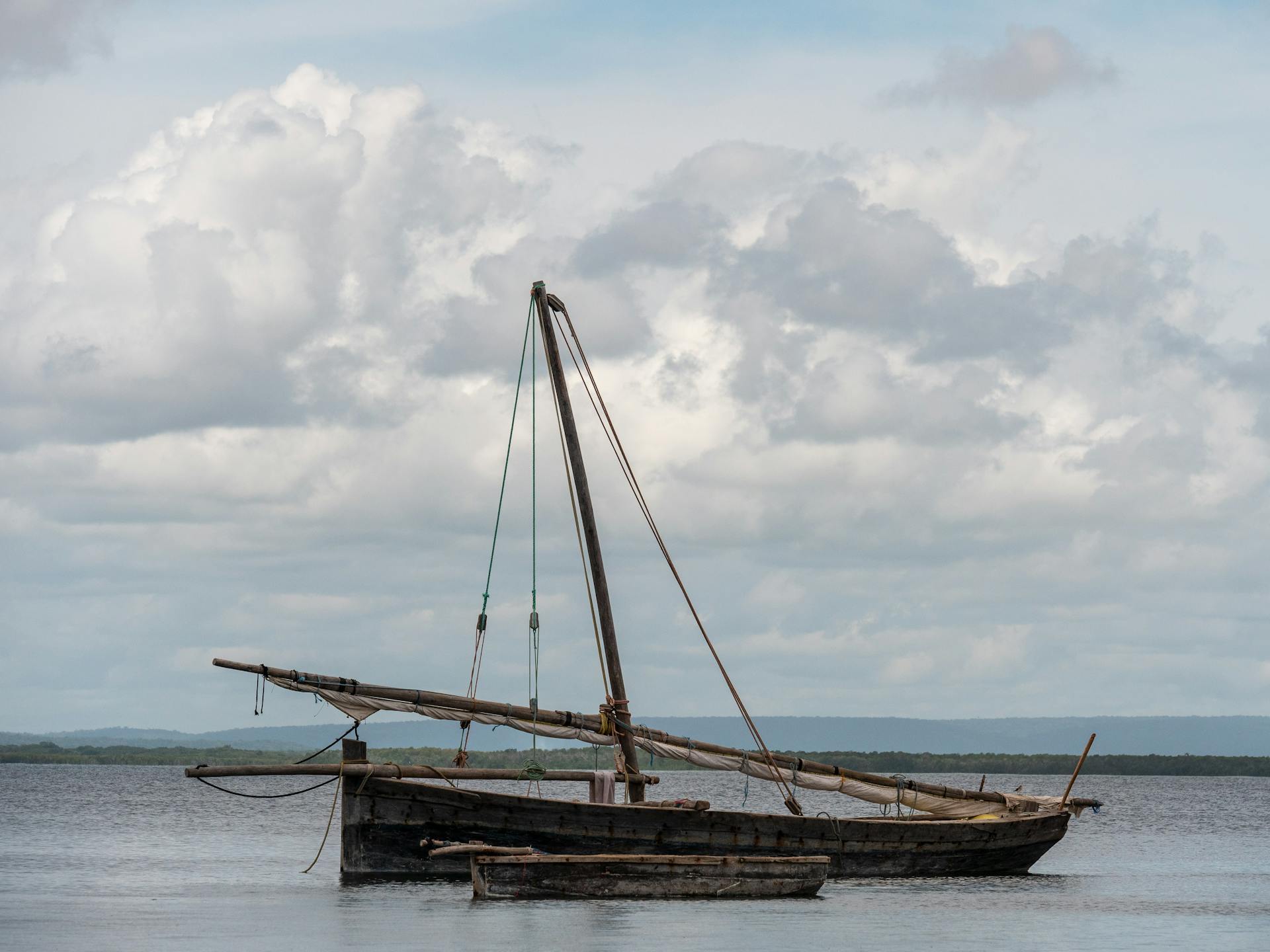 A traditional dhow sailing boat floating on the calm sea near Kilwa Kisiwani, Tanzania.
