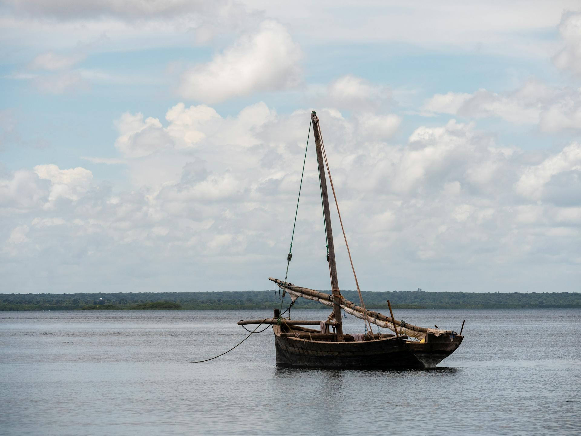 A serene view of a traditional wooden dhow sailing on the waters near Kilwa Kisiwani, Tanzania.