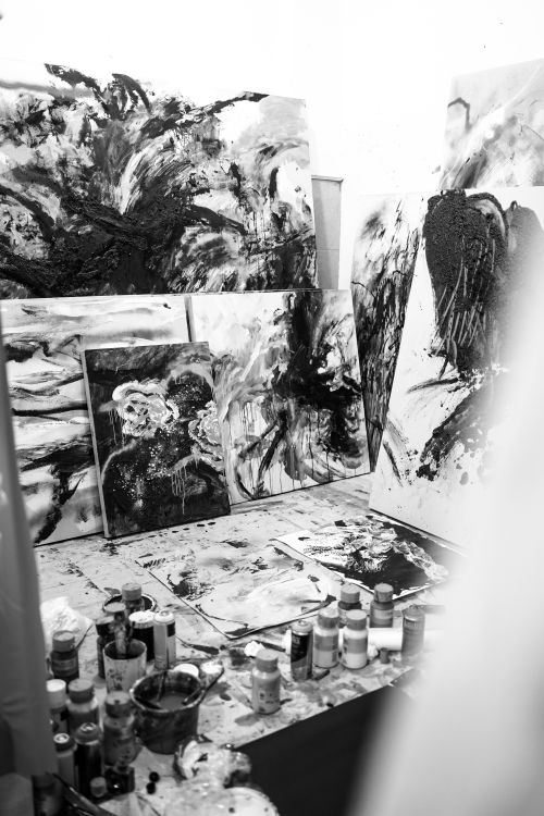 Free Black and white photo of an art studio filled with abstract paintings and painting supplies. Stock Photo