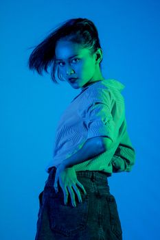 Dynamic portrait of a young woman with striking blue lighting, showcasing modern fashion and bold attitude.
