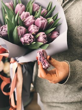 一束紫色郁金香的特写镜头中，一只手拿着配套的马卡龙