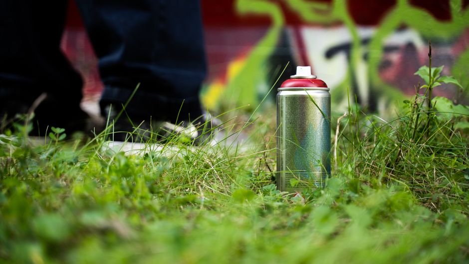Is eco-friendly cabinet painting in Denver worth it for families? 2 Close-up of a spray paint can on grass, part of an urban graffiti scene.