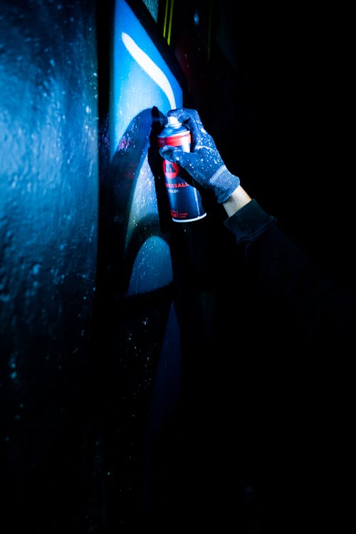 A Person Wearing a Glove Spray Painting a Wall
