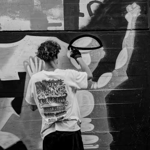 Free Back view of a street artist spray painting graffiti artwork on a wall. Stock Photo