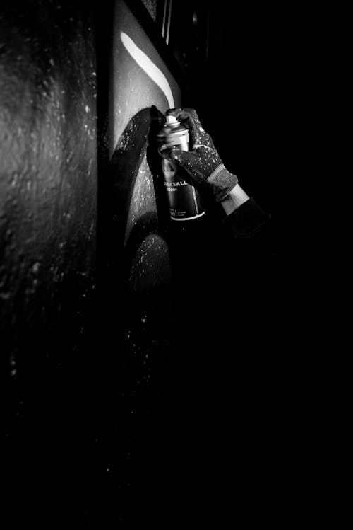 Grayscale Photo of a Person Using a Spray Paint