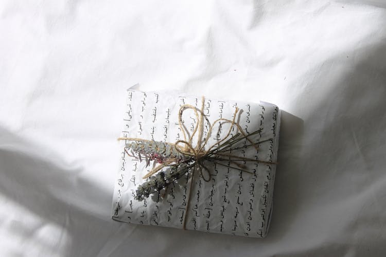 A Gift Wrapped In Paper With Dried Flowers