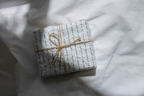Free Beautifully wrapped gift with Arabic script wrapping paper and twine bow on a white surface. Stock Photo