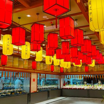 Colorful red and yellow paper lanterns hanging in an Asian restaurant interior.（イメージ）