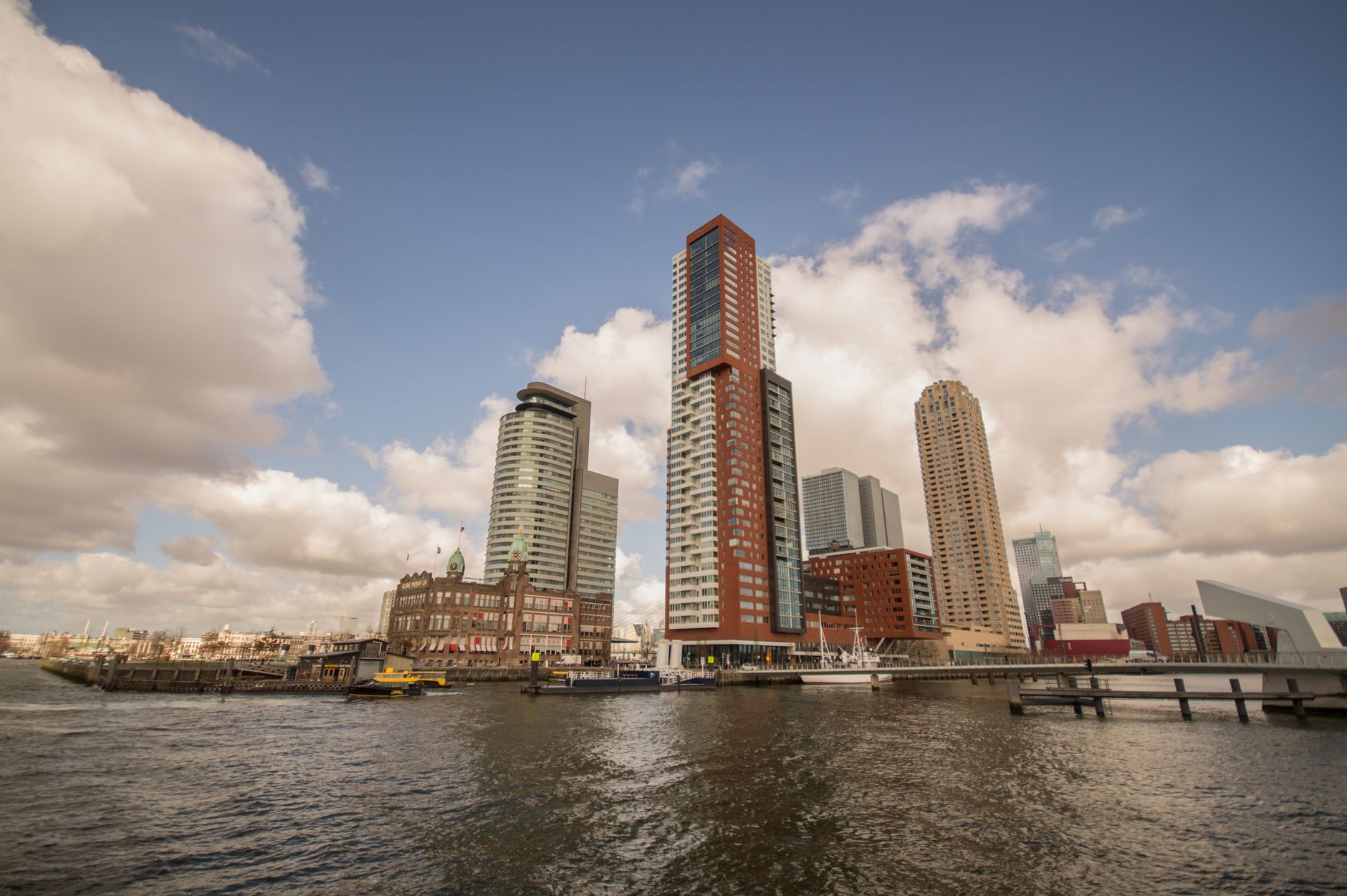 A stunning view of Rotterdam's skyline featuring modern skyscrapers along the waterfront under a cloudy sky.