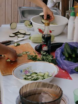 Hands slicing vegetables for a fresh salad indoors, showcasing preparation steps with vibrant ingredients.