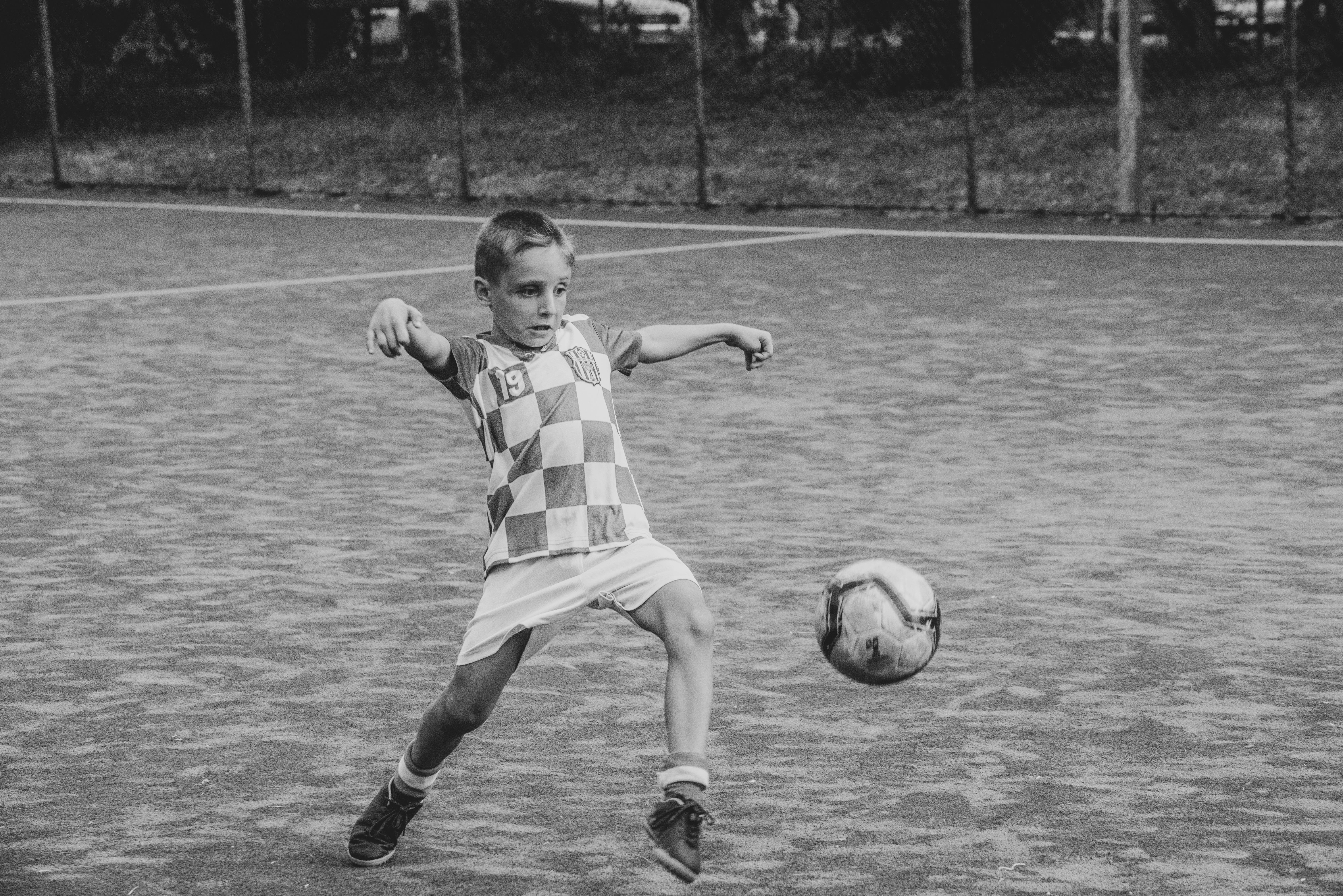grayscale photo of boy playing soccer
