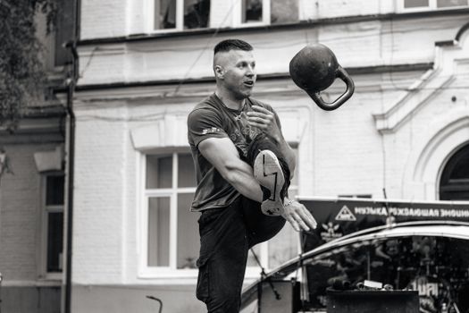 Man performing kettlebell trick in city street displaying strength and skill.