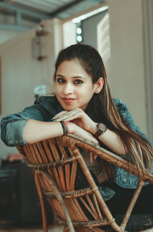 Free Casual portrait of a smiling woman sitting outdoors on a wooden chair. Stock Photo