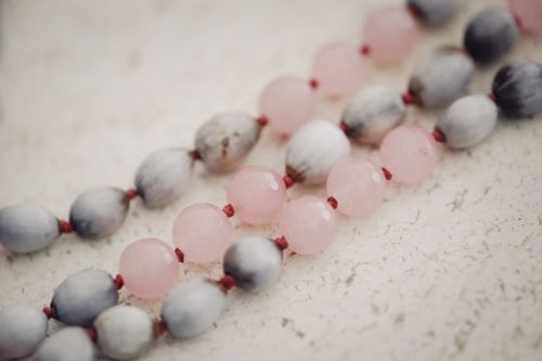 Free Close-up image of pink and gray beads on a textured white surface, showcasing elegance and simplicity. Stock Photo