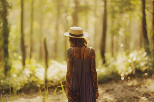 Free A woman with tattoos enjoys a peaceful walk in a sunlit forest, embracing nature. Stock Photo