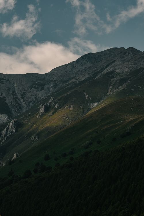 Free A breathtaking view of a rugged mountain slope under a partially cloudy sky, showcasing natural beauty. Stock Photo