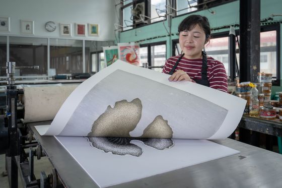 Printmaker lifting a fresh sheet off the press bed - photo by Thoranin Duangsin on Pexels