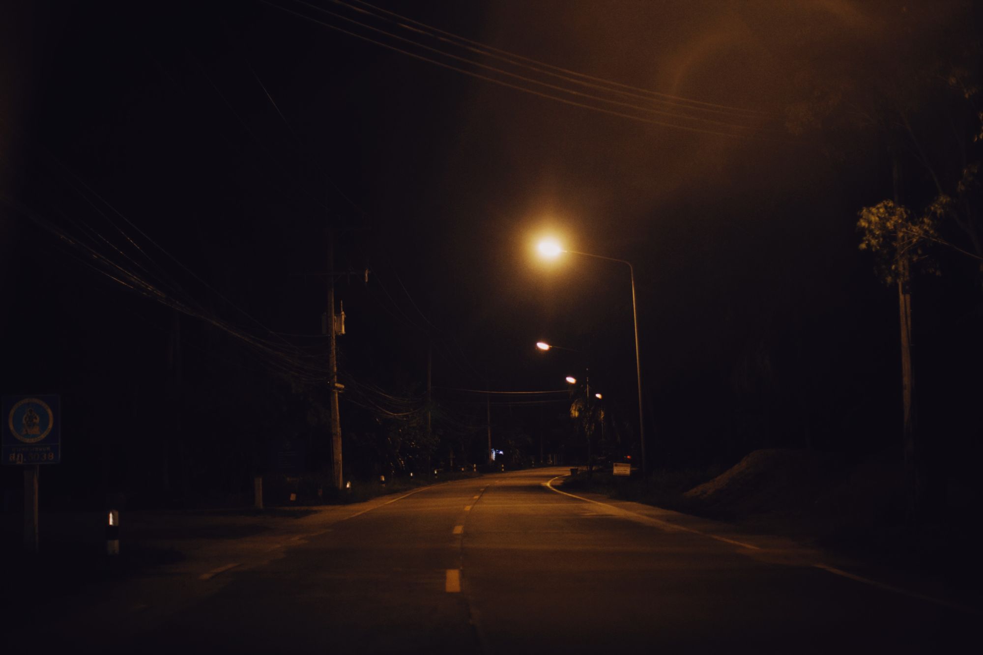 A serene nighttime street scene with glowing street lamps along an empty road.