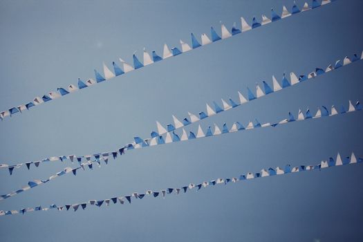 Low angle view of blue and white bunting flags in the sky, ideal for festive and decorative themes.