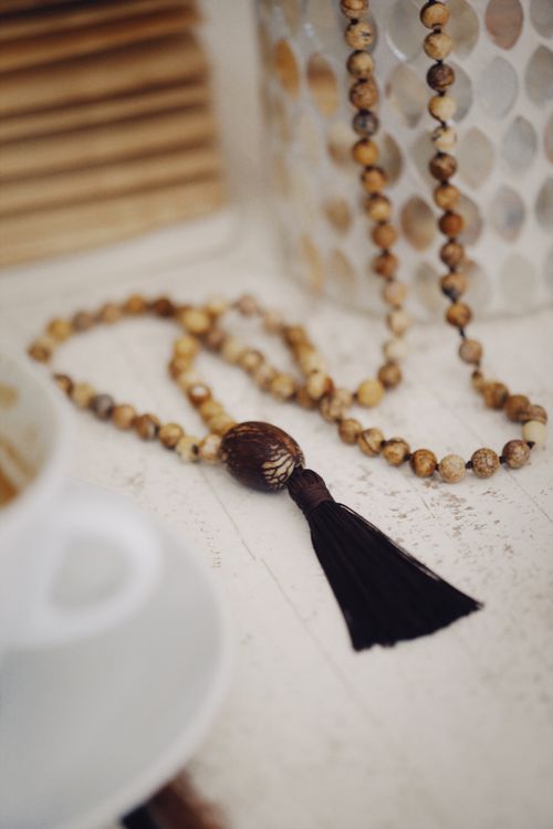 Free Close-up of a handmade wooden beaded necklace with a tassel, elegantly displayed indoors. Stock Photo