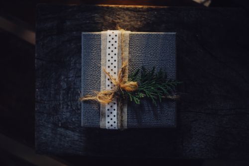 Free Elegant rustic gift box with polka dot ribbon and fern decoration on a dark wooden background. Stock Photo