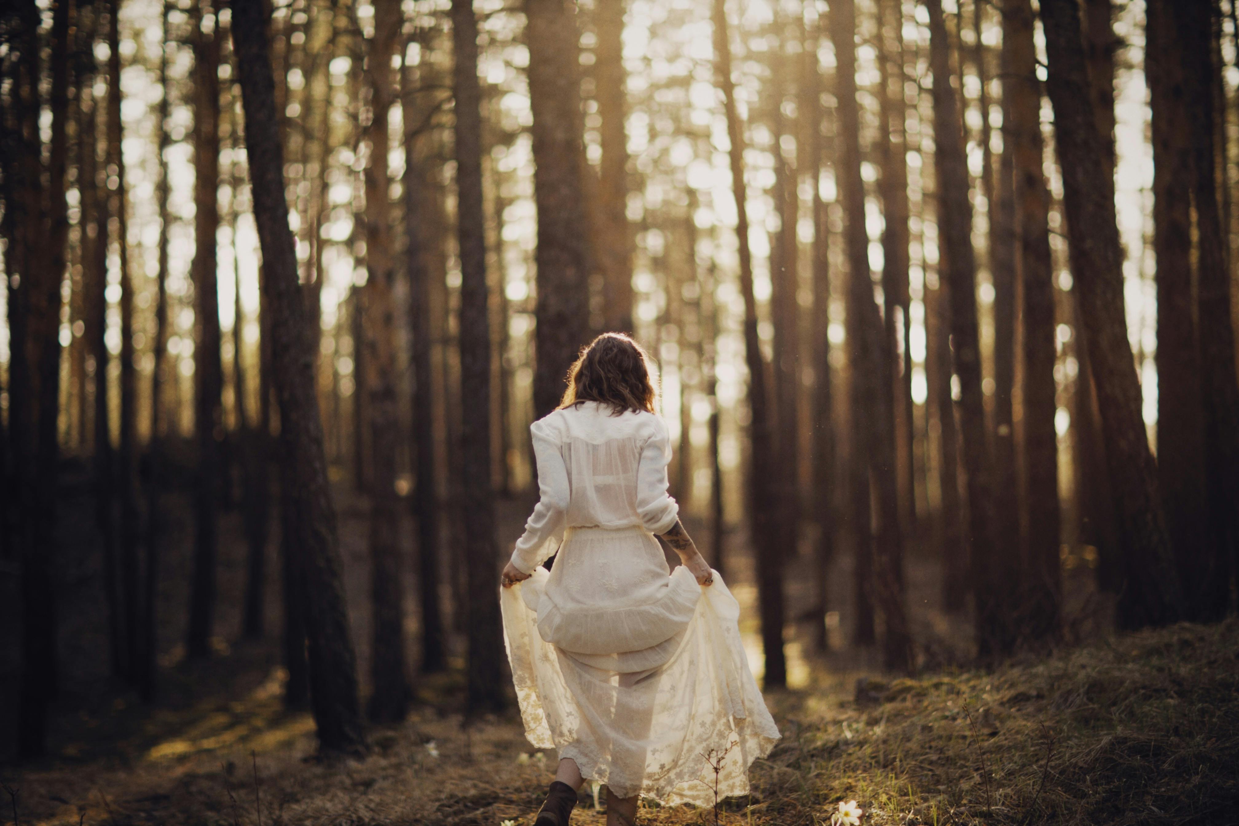 a woman lifting her skirt while walking in the forest