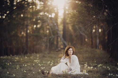 Woman in White Dress Sitting on Grass Field