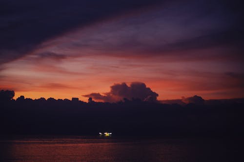 Silhouette of Boat Sailing on the Sea during Evening Sky