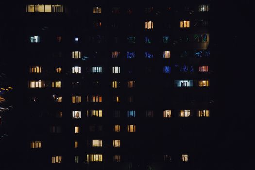 A night view of a residential apartment building with lit windows showcasing city life.