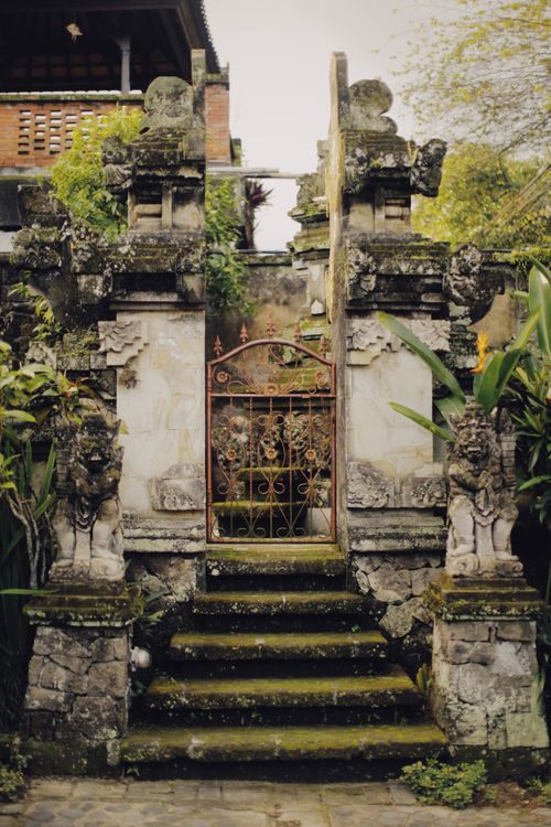 Free Intricately carved temple entrance surrounded by greenery, featuring moss-covered stairs. Stock Photo