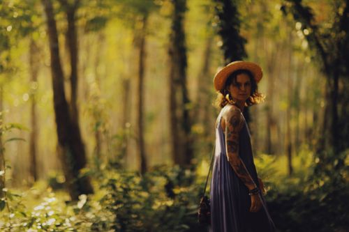 Free Tattooed woman in a dress and hat walks through tranquil forest setting. Stock Photo