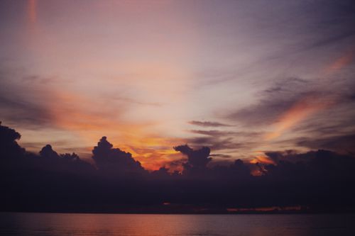 Free Captivating dawn sky with orange and purple hues over a calm sea, promising a peaceful day. Stock Photo