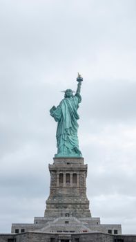 Rear view of the Statue of Liberty against a cloudy sky in New York City.