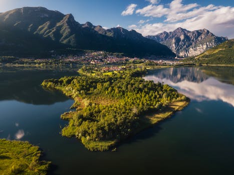 Stunning aerial shot of an Italian lake surrounded by lush greenery and mountains.