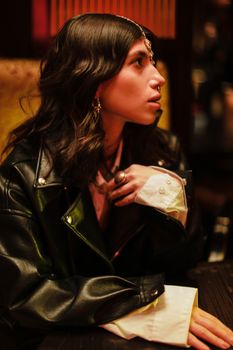 Woman in Black Leather Jacket Sitting on a Chair while Looking Afar