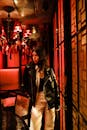 Woman in Black Leather Jacket Standing Beside Brown Wooden Chair