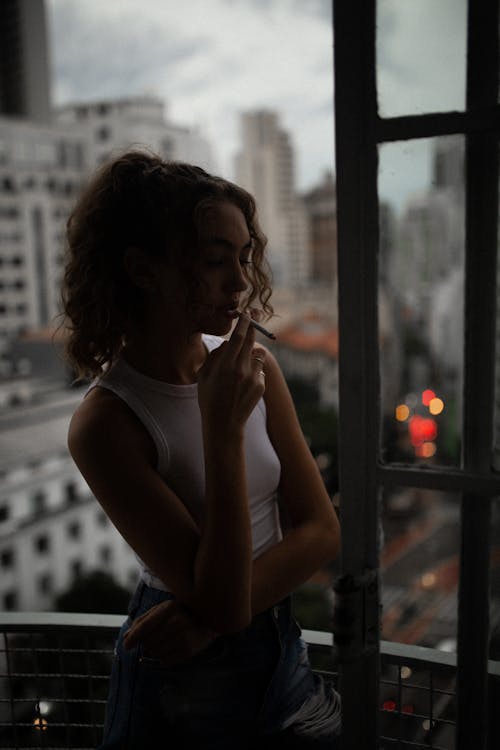 Free Woman in Smoking Cigarette by the Open Window Stock Photo