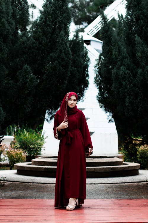 Woman in Traditional Red Dress and Scarf Posing with White Windmill